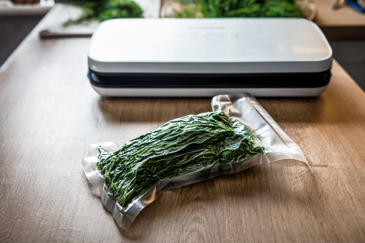 Vakuummaskin på träbord med ett vakuumförpackat knippe örter